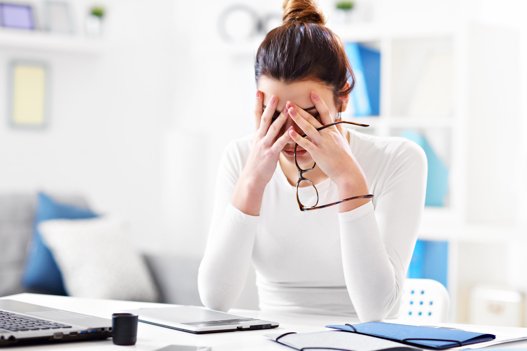 tired woman in office with head in hands